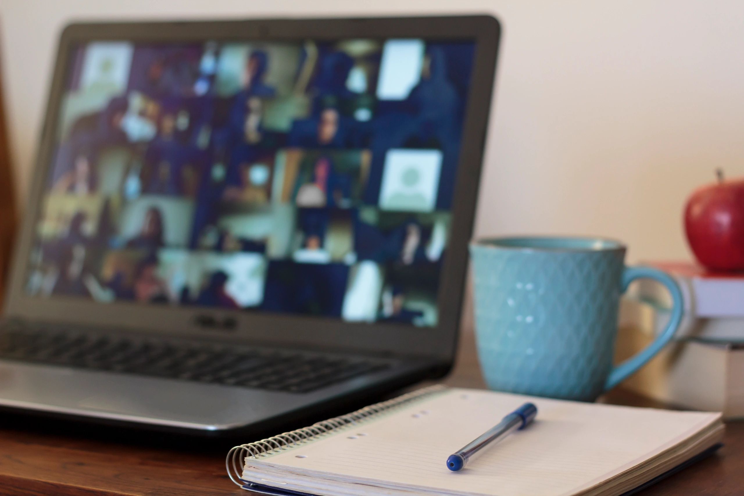 A laptop and notebook on a desk with a cup of coffee.